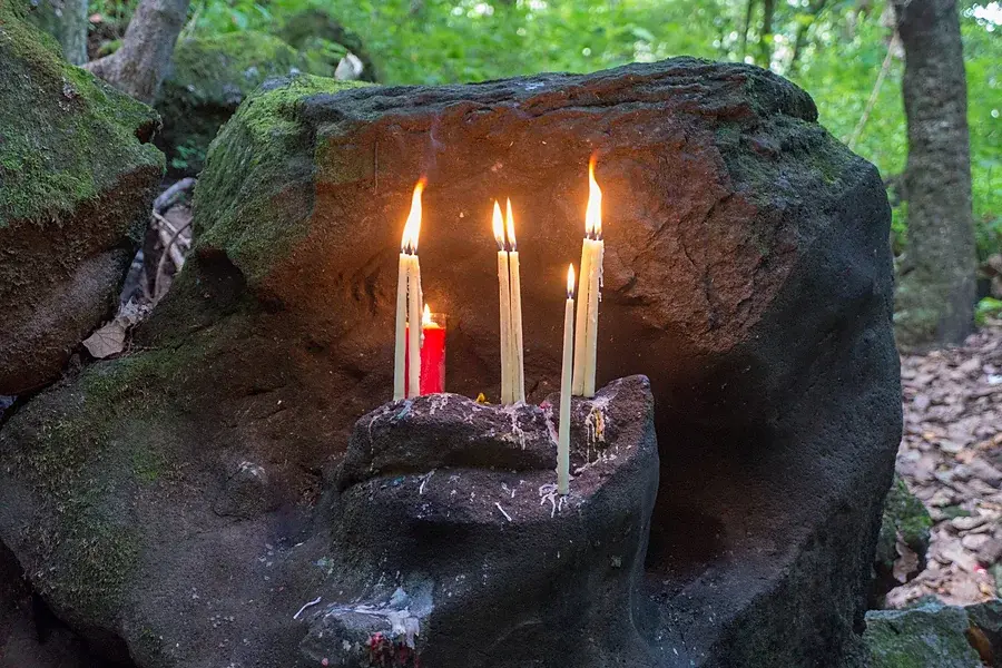 Brennende Kerzen auf einem bemoosten Steinaltar