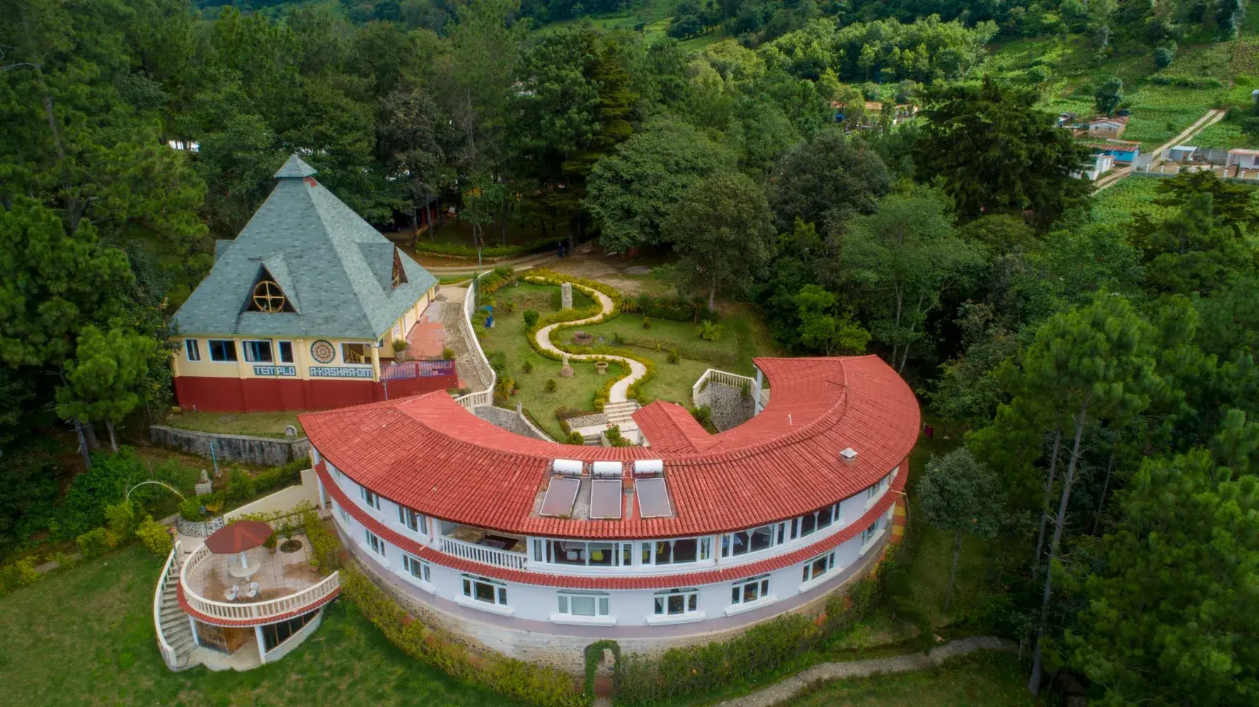 Das Zentrum Paz Mundo von oben, der geschwungene Hauptbau im Wald